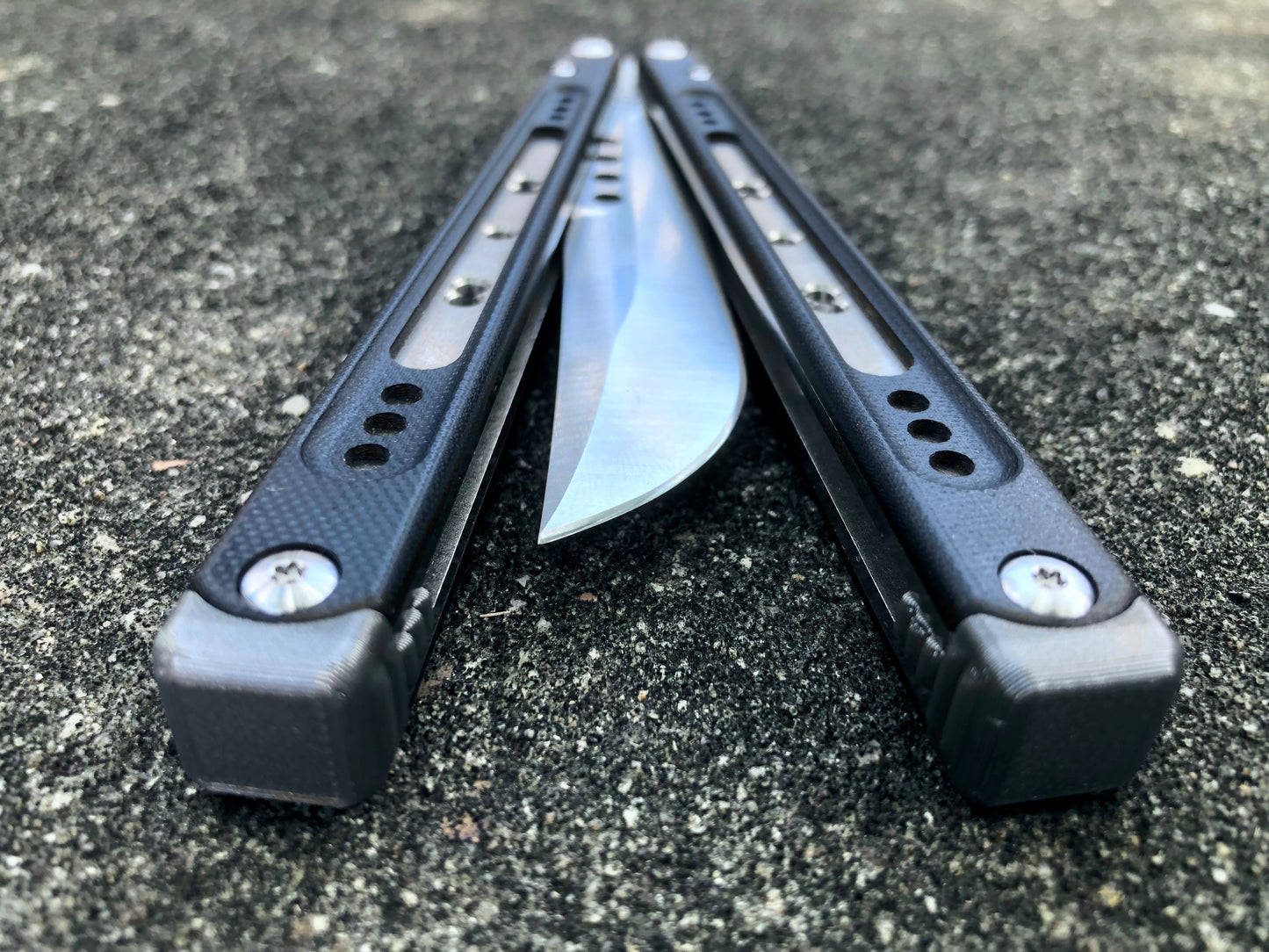 These Black Balisong Rebola v2 spacers are made in-house from a rubbery, shatter-proof polyurethane. They are ultra-lightweight extension spacers that reduce the stock handle-bias. They also feature positive sawtooth jimping and enable adjustable balance with up to 1x removable tungsten weight per spacer.