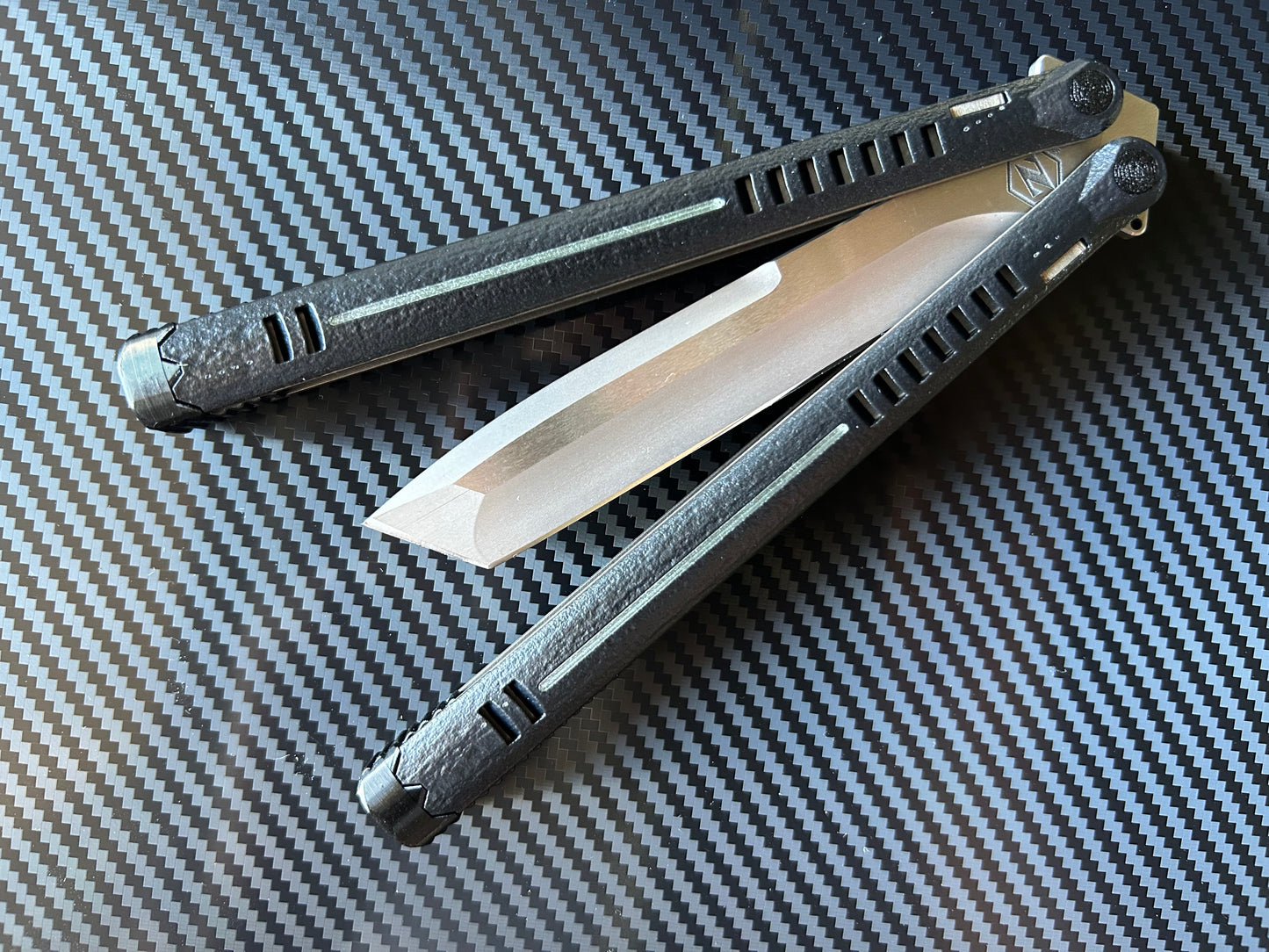 The Parallax is Zippy's first metal butterfly knife, featuring and a modular spacer system that enables rapid adjustment of handle length and balance. The innovative triple-liner design and channel scales provide enhanced rigidity compared to traditional sandwich-style balisongs. The Parallax features threadlocker-free tuning and the high-performance raceway bearing system, which is slower and more controlled compared to traditional bearings.