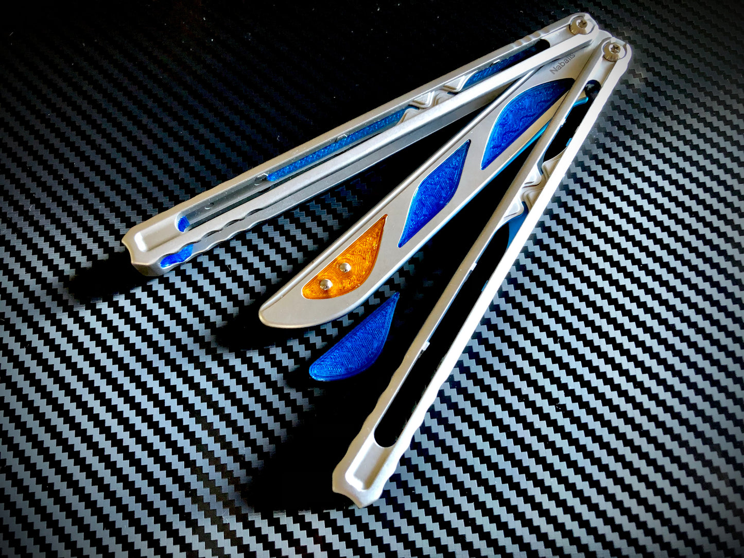 Deepen the sound, silence the ring and adjust the weight distribution of your Nabalis Canyon balisong these custom-made Zippy inlays. This mod consists of (1) speed channel inlays which silence 90% of the ring; as well as optional (2) jimping plugs which silence the ring and house a removable tungsten weight for handle-bias lovers; and (3) optional trainer blade inserts to add tip-weight and a pop of color.