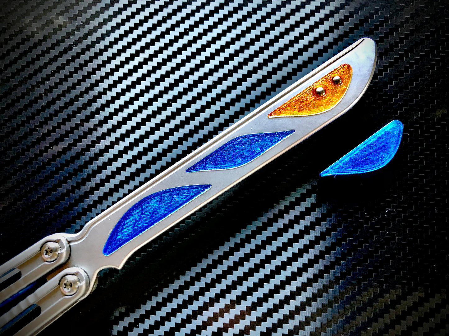 Deepen the sound, silence the ring and adjust the weight distribution of your Nabalis Canyon balisong these custom-made Zippy inlays. This mod consists of (1) speed channel inlays which silence 90% of the ring; as well as optional (2) jimping plugs which silence the ring and house a removable tungsten weight for handle-bias lovers; and (3) optional trainer blade inserts to add tip-weight and a pop of color.