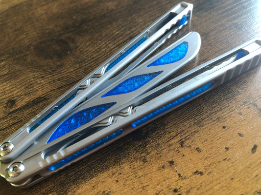 Silence the ring and adjust the weight distribution of your Nabalis Canyon balisong these custom-made Zippy inlays